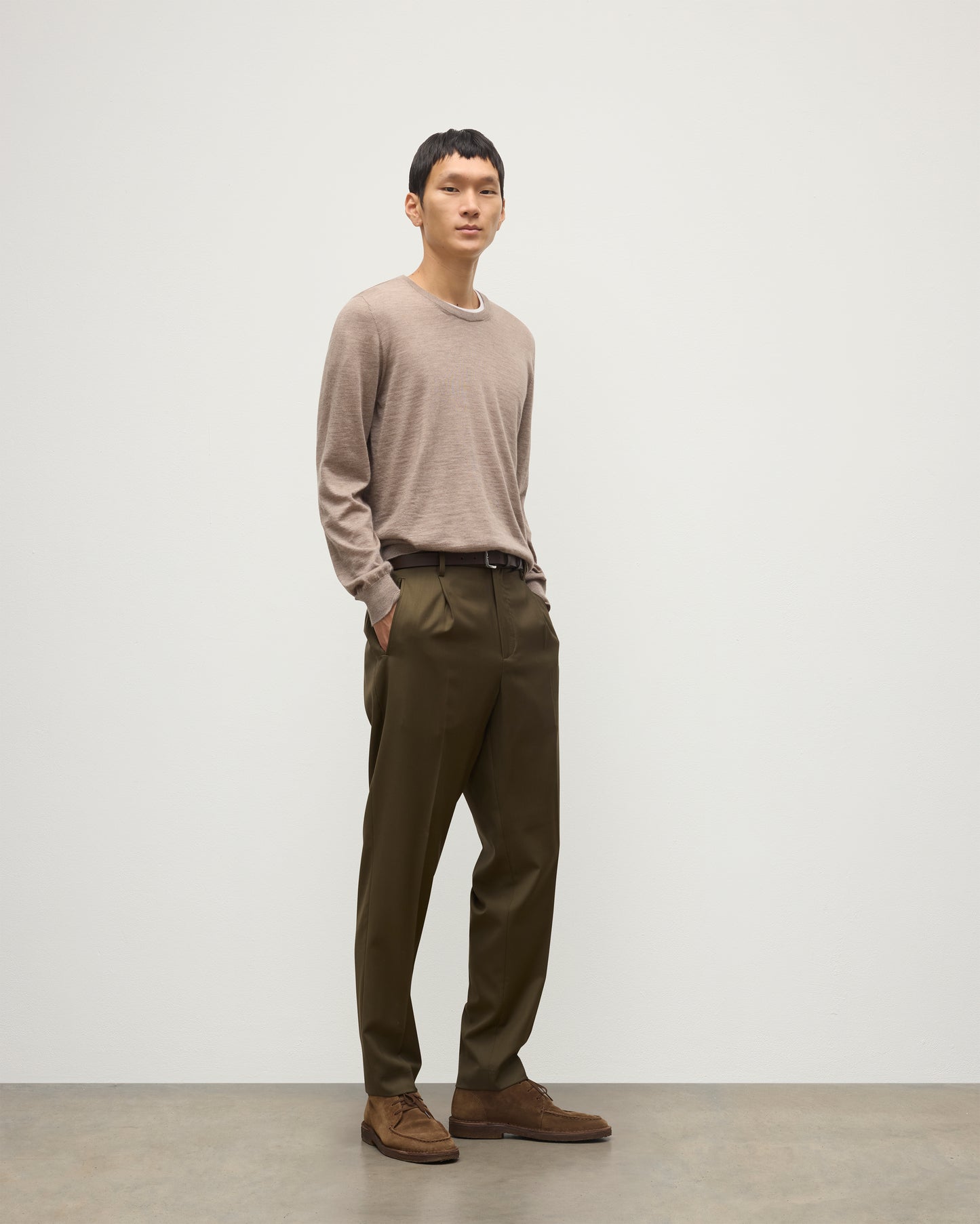 MODEL WEARS JOHNSTONS OF ELGIN MENS FIN SUPERFINE CREW LIGHT BROWN 100% SUPERFINE CASHMERE OVER A WHITE T-SHIRT WITH OLIVE GREEN TROUSERS  KAI05717HB0273