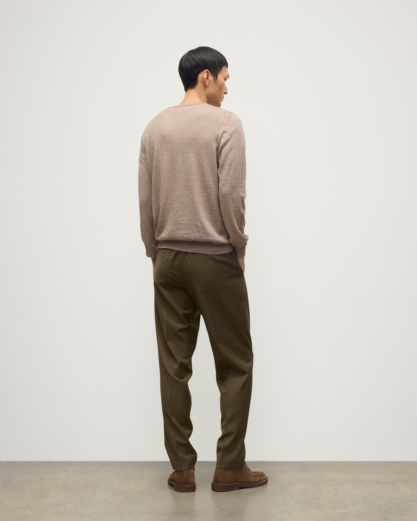 MODEL WEARS JOHNSTONS OF ELGIN MENS FIN SUPERFINE CREW LIGHT BROWN 100% SUPERFINE CASHMERE OVER A WHITE T-SHIRT WITH OLIVE GREEN TROUSERS  KAI05717HB0273