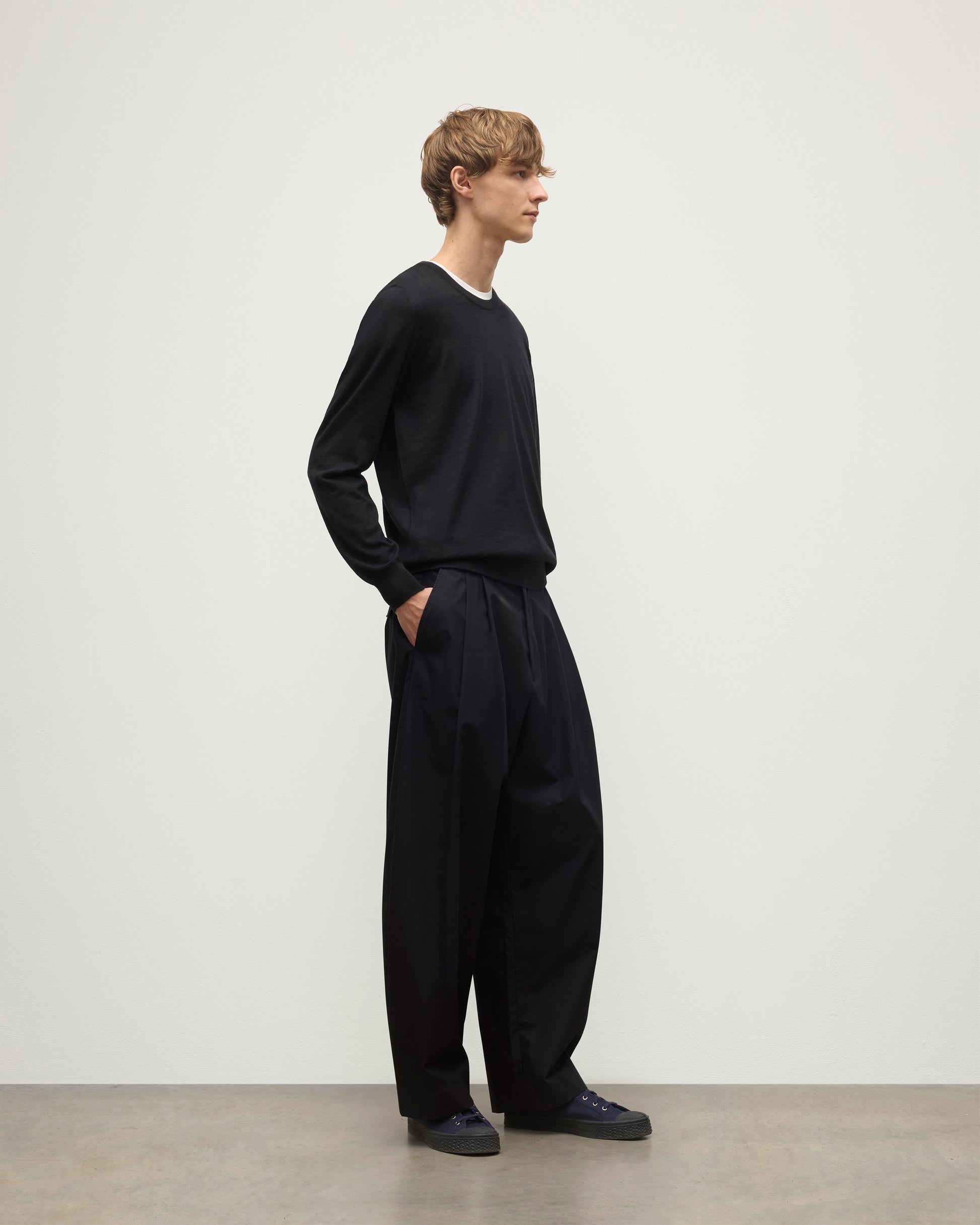 MODEL WEARS JOHNSTONS OF ELGIN MENS FIN SUPERFINE CREW BLACK 100% SUPERFINE CASHMERE OVER A WHITE T-SHIRT WITH BLACK TROUSERS KAI05717SA7146