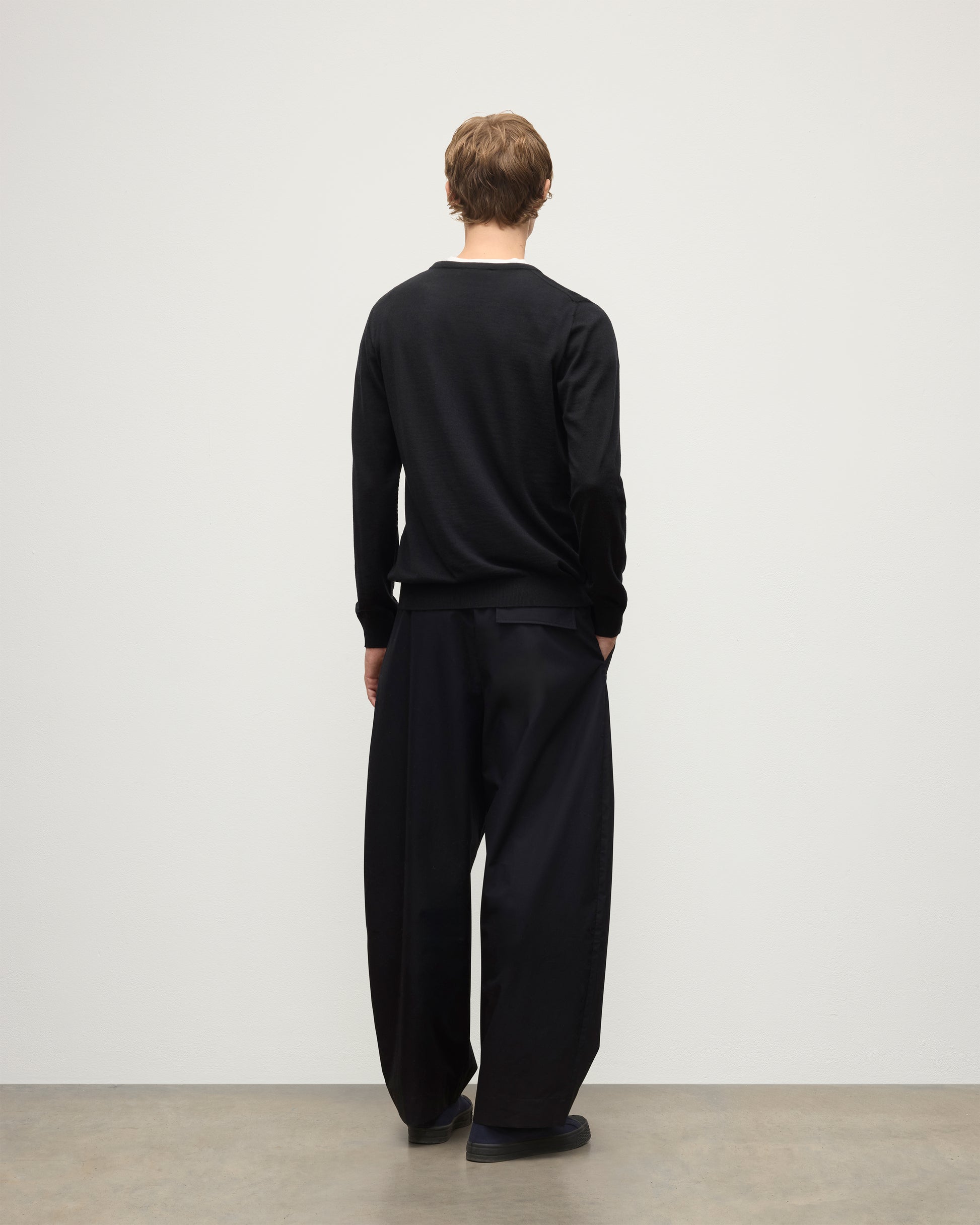 MODEL WEARS JOHNSTONS OF ELGIN MENS FIN SUPERFINE CREW BLACK 100% SUPERFINE CASHMERE OVER A WHITE T-SHIRT WITH BLACK TROUSERS KAI05717SA7146