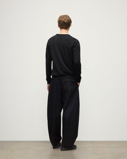 MODEL WEARS JOHNSTONS OF ELGIN MENS FIN SUPERFINE CREW BLACK 100% SUPERFINE CASHMERE OVER A WHITE T-SHIRT WITH BLACK TROUSERS KAI05717SA7146