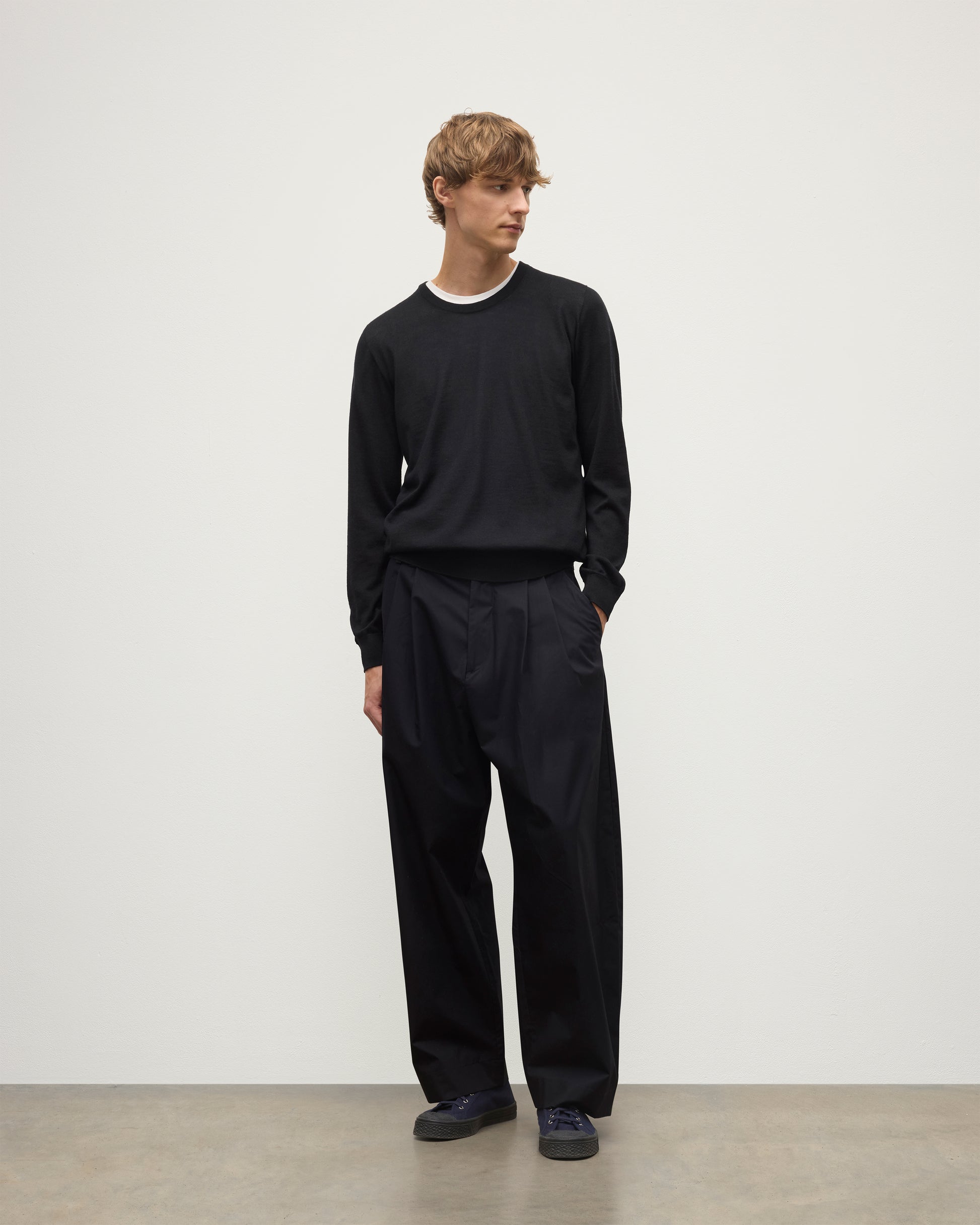 MODEL WEARS JOHNSTONS OF ELGIN MENS FIN SUPERFINE CREW BLACK 100% SUPERFINE CASHMERE OVER A WHITE T-SHIRT WITH BLACK TROUSERS KAI05717SA7146