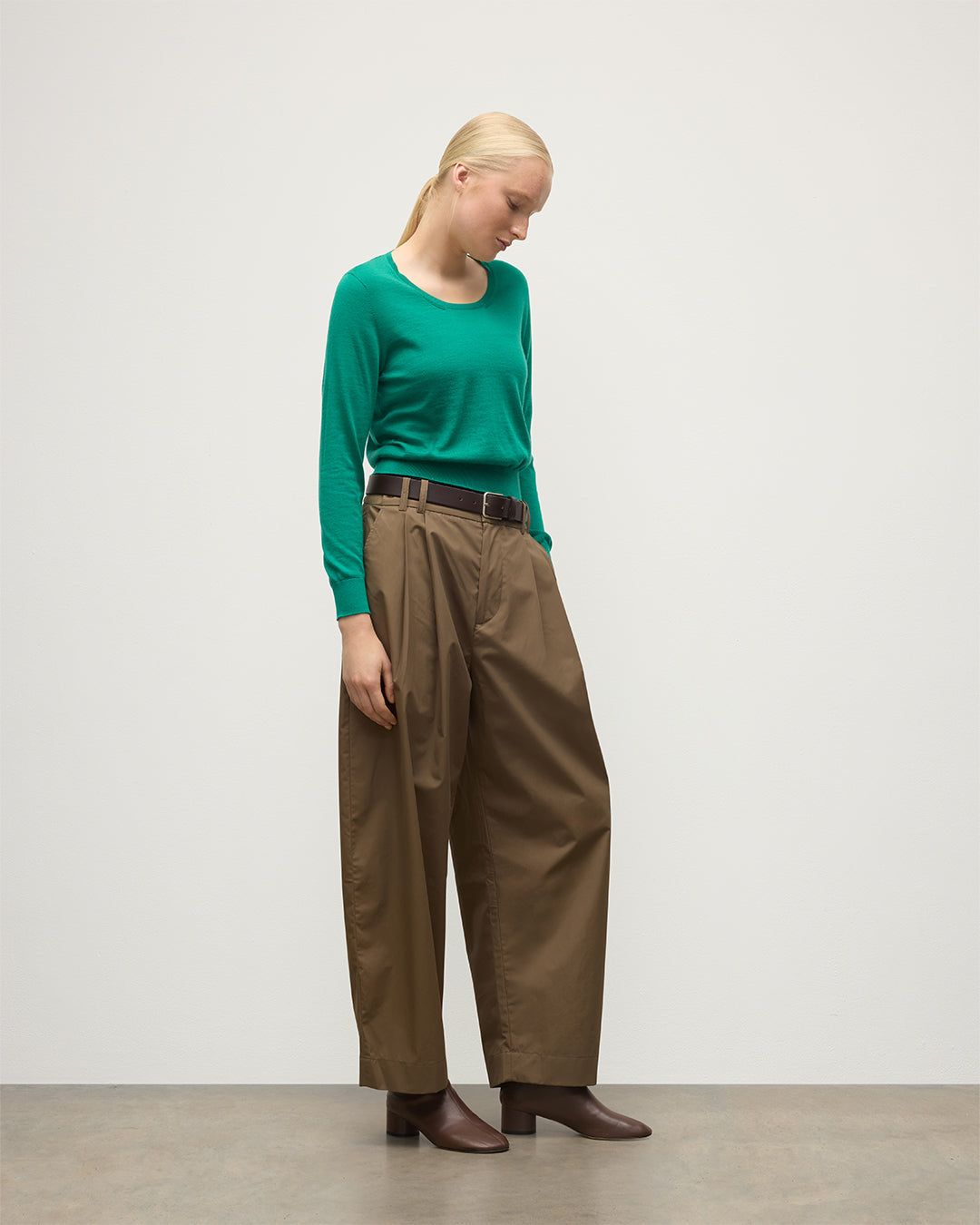 MODEL WEARS JOHNSTONS OF ELGIN WOMENS ELLA SCOOP SWEATER GREEN 100% SUPERFINE CASHMERE WITH BROWN WIDE LEG TROUSERS  KAI05723SC4714