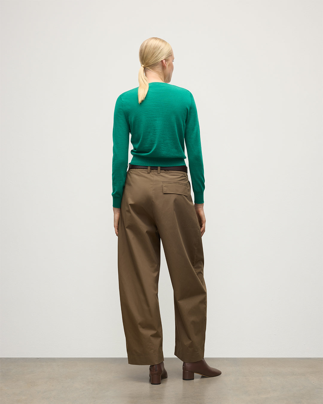 MODEL WEARS JOHNSTONS OF ELGIN WOMENS ELLA SCOOP SWEATER GREEN 100% SUPERFINE CASHMERE WITH BROWN WIDE LEG TROUSERS  KAI05723SC4714