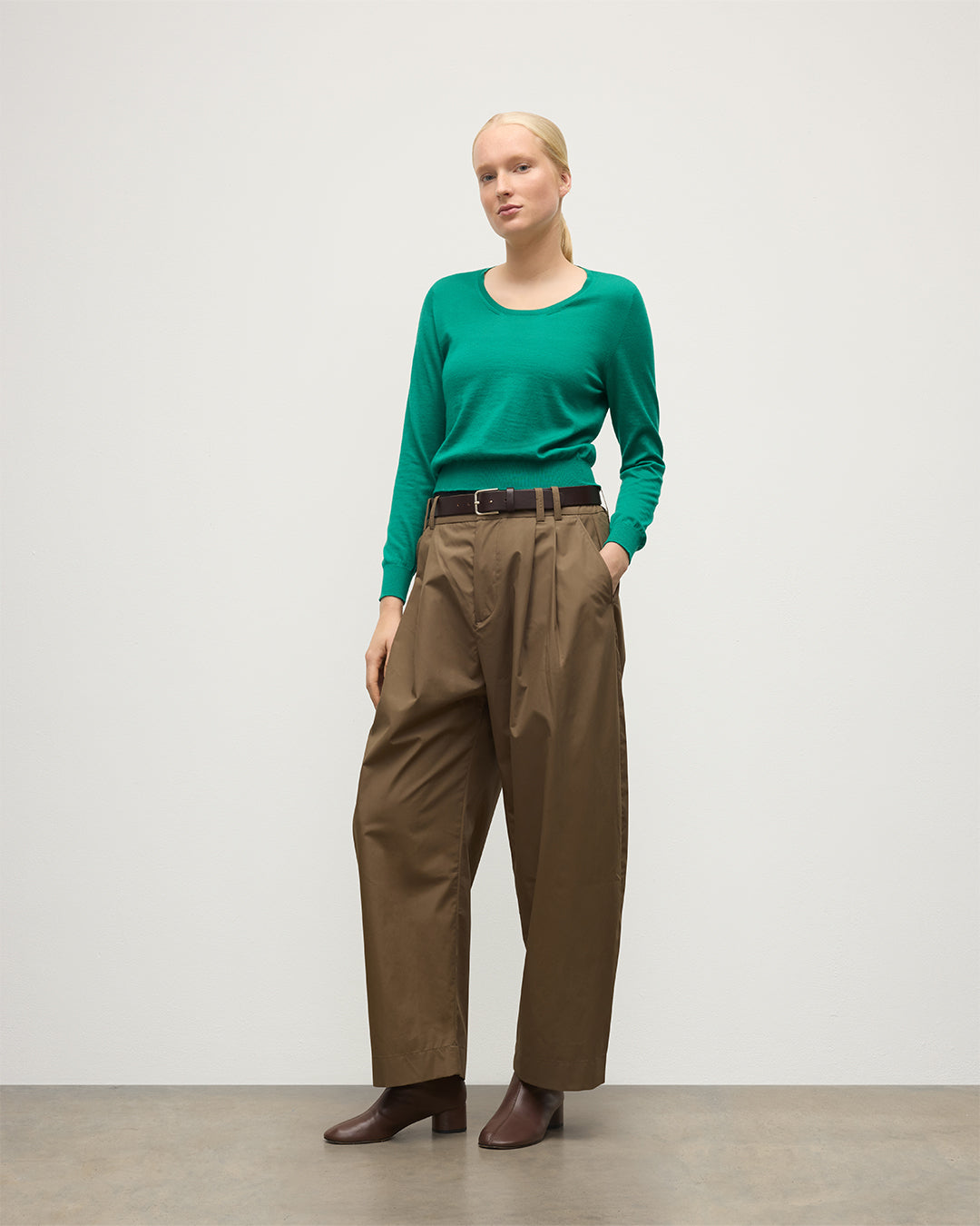 MODEL WEARS JOHNSTONS OF ELGIN WOMENS ELLA SCOOP SWEATER GREEN 100% SUPERFINE CASHMERE WITH BROWN WIDE LEG TROUSERS  KAI05723SC4714