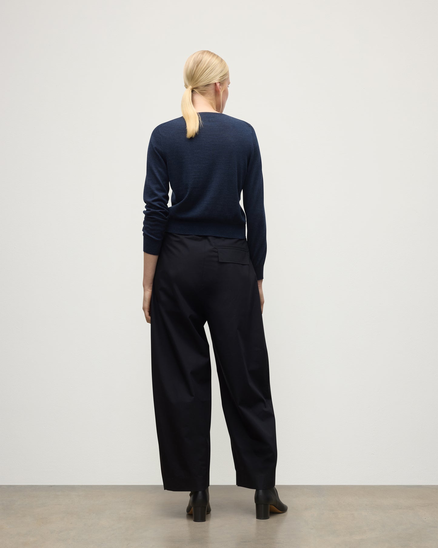 MODEL WEARING JOHNSTONS OF ELGIN WOMENS ELLA SCOOP SWEATER NAVY WITH BLACK TROUSERS AND BOOTS KAI05723HD7350