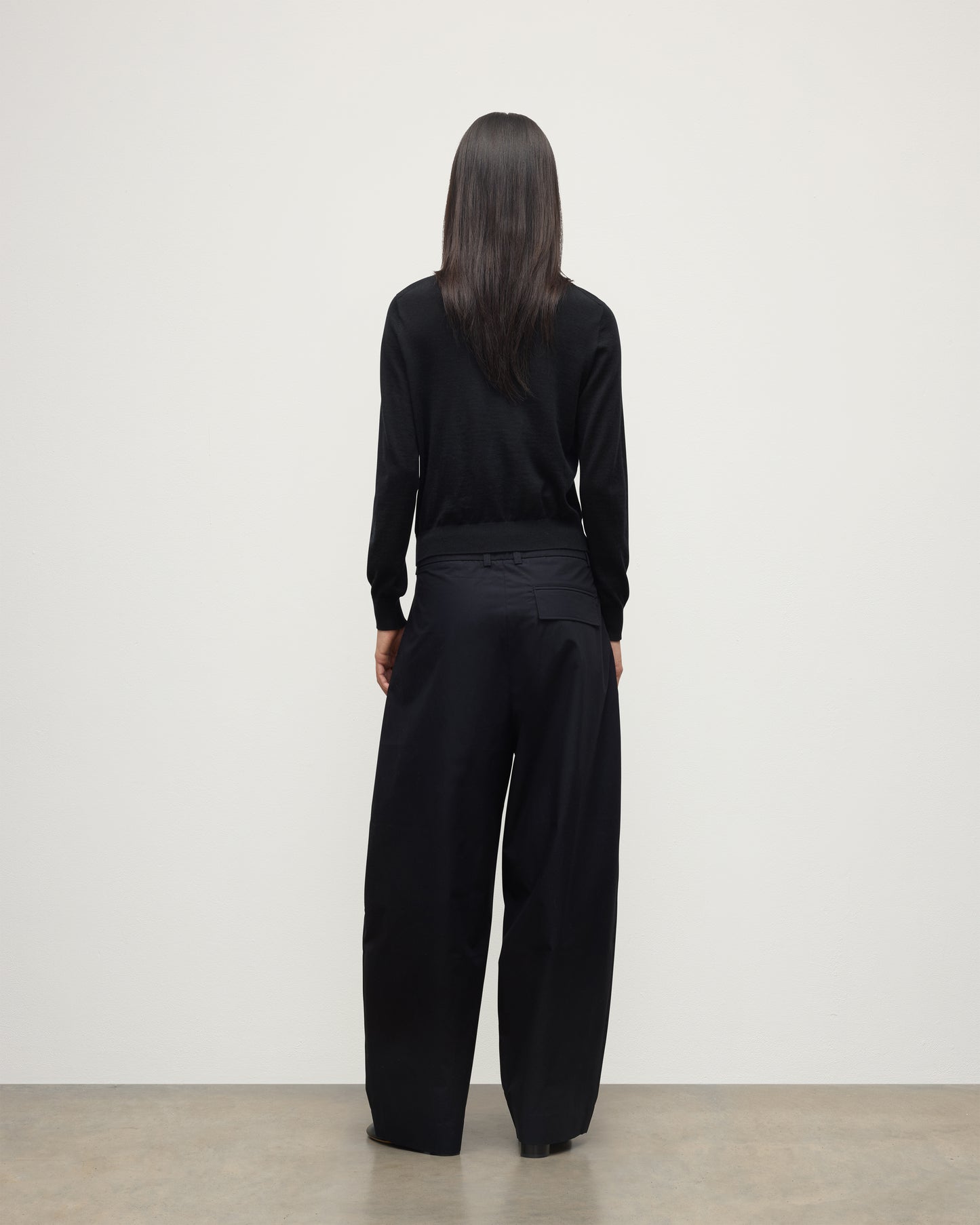 BACK VIEW OF MODEL WEARING JOHNSTONS OF ELGIN WOMENS ELLA SCOOP SWEATER BLACK WITH BLACK TROUSERS KAI05723SA7146