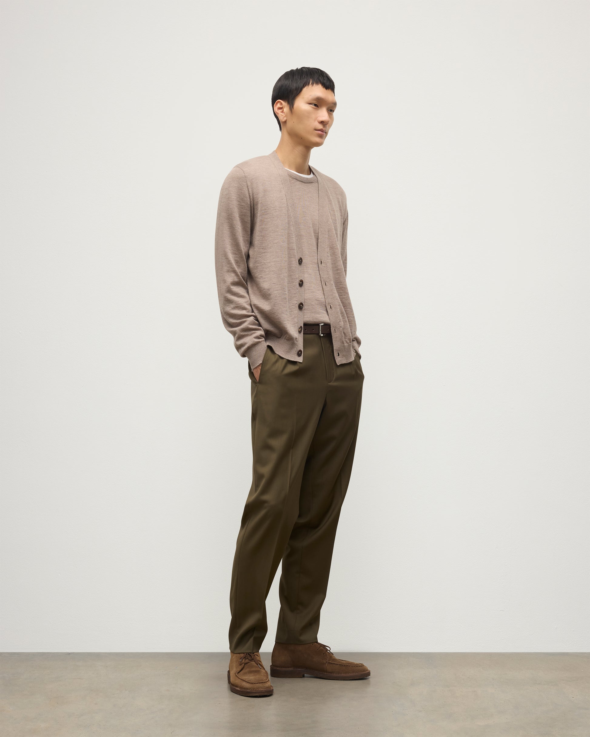 MALE MODEL WEARING JOHNSTONS OF ELGIN FORSYTH SUPERFINE VEE NECK CARDIGAN LIGHT BROWN  OVER A MATCHING SUPERFINE CASHMERE SWEATER AND OLIVE TROUSERS KAI05740HB0273