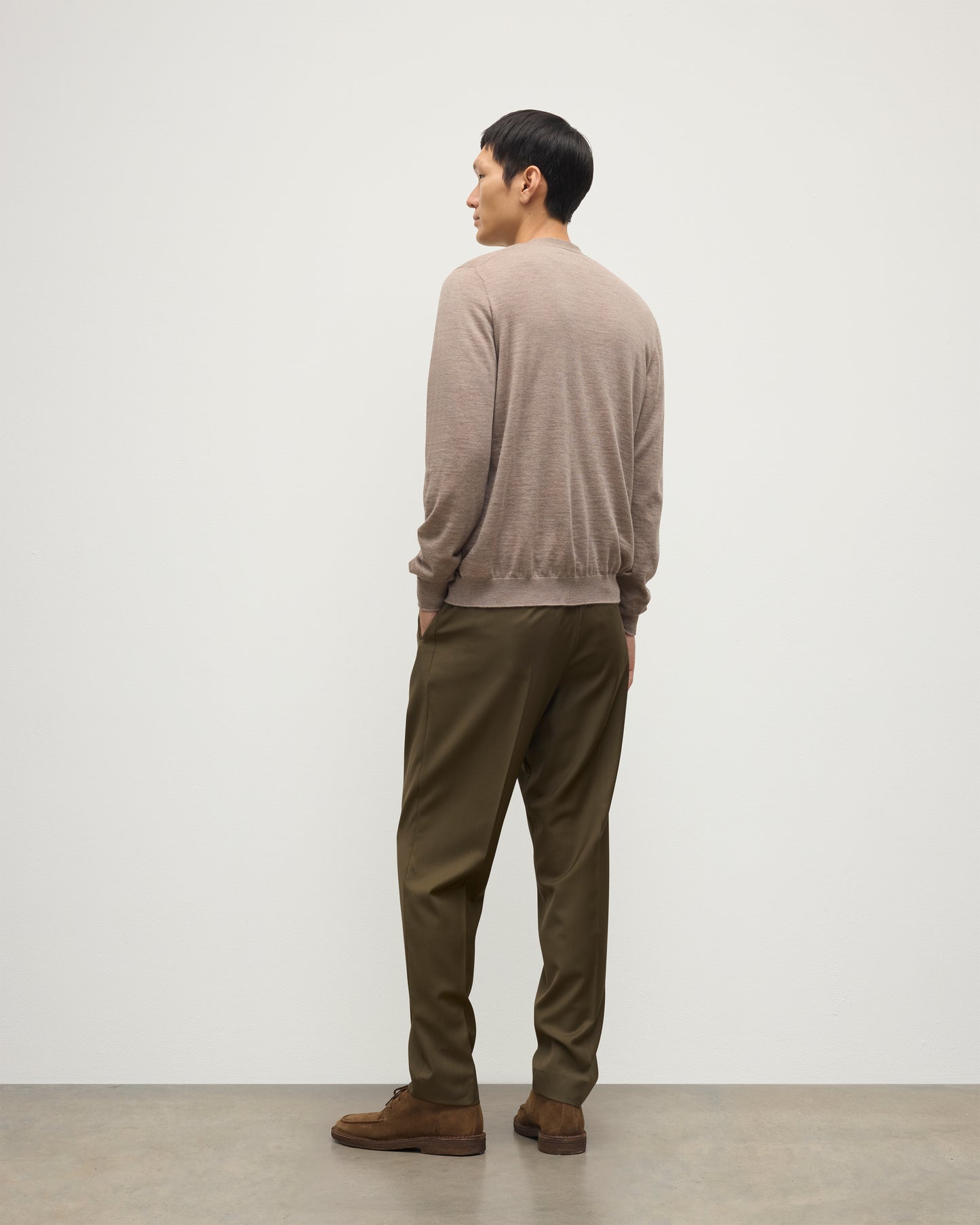 MALE MODEL WEARING JOHNSTONS OF ELGIN FORSYTH SUPERFINE VEE NECK CARDIGAN LIGHT BROWN  OVER A MATCHING SUPERFINE CASHMERE SWEATER AND OLIVE TROUSERS KAI05740HB0273