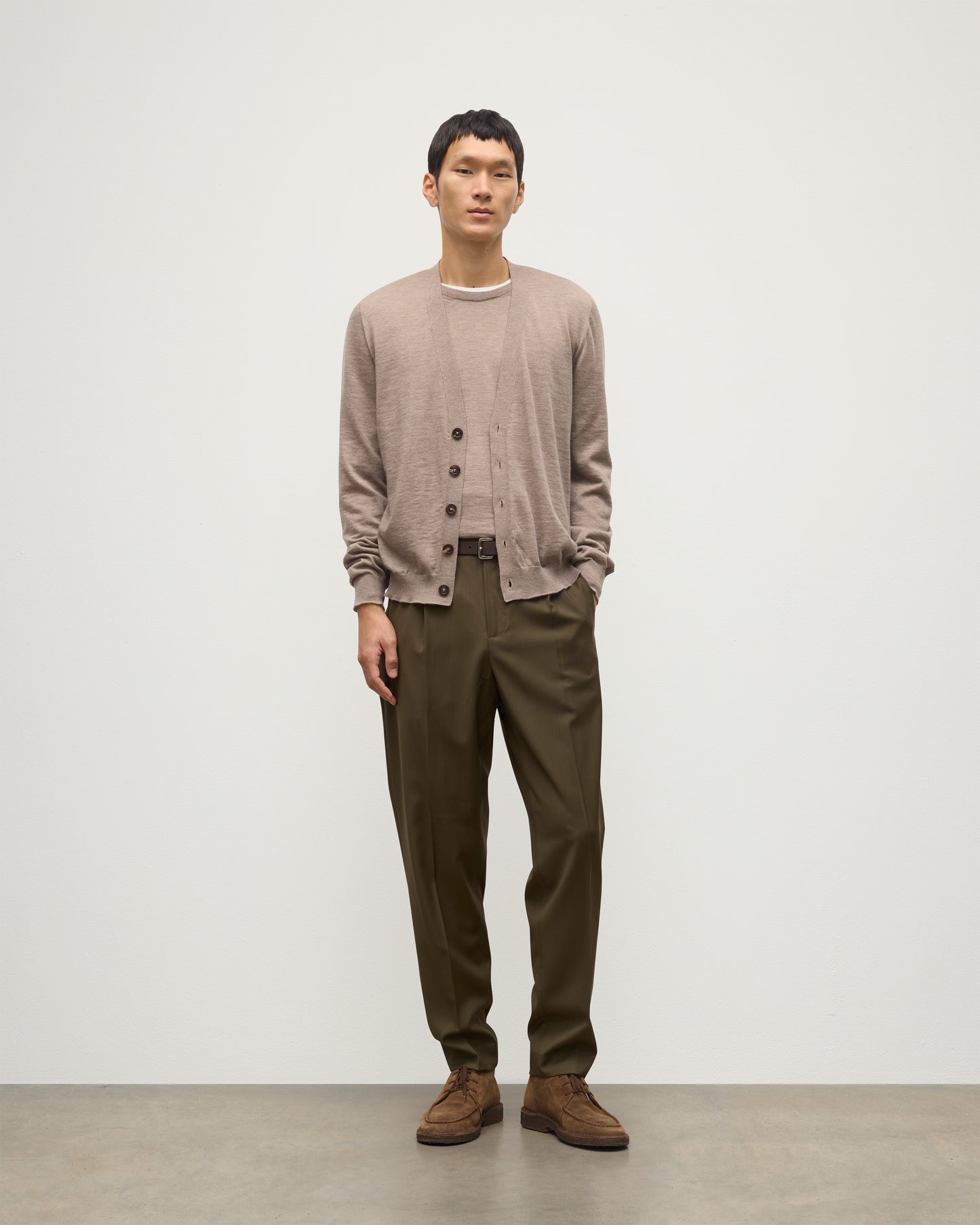 MALE MODEL WEARING JOHNSTONS OF ELGIN FORSYTH SUPERFINE VEE NECK CARDIGAN LIGHT BROWN  OVER A MATCHING SUPERFINE CASHMERE SWEATER AND OLIVE TROUSERS KAI05740HB0273