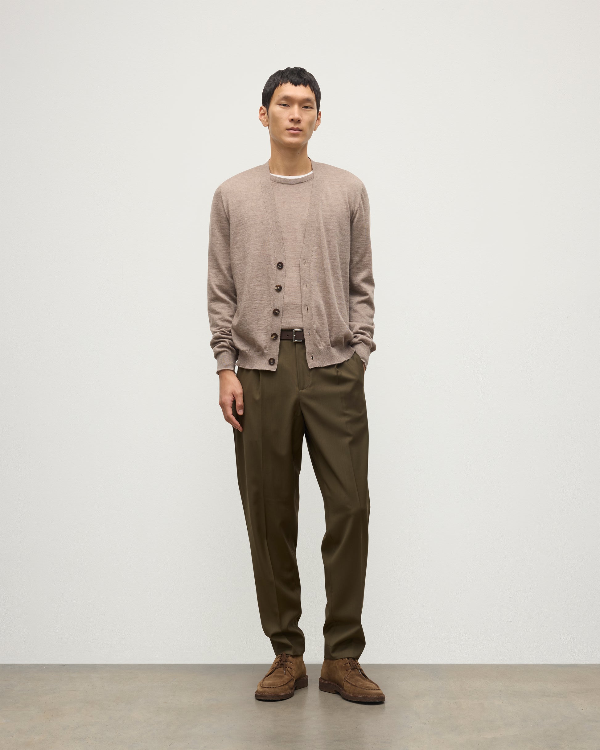 MALE MODEL WEARING JOHNSTONS OF ELGIN FORSYTH SUPERFINE VEE NECK CARDIGAN LIGHT BROWN  OVER A MATCHING SUPERFINE CASHMERE SWEATER AND OLIVE TROUSERS KAI05740HB0273