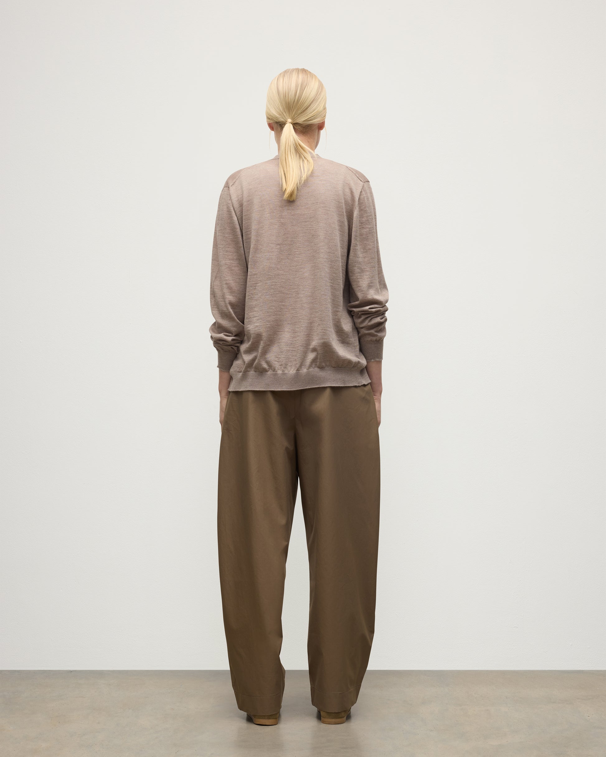 FEMALE MODEL WEARING JOHNSTONS OF ELGIN FORSYTH SUPERFINE VEE NECK CARDIGAN LIGHT BROWN WITH BROWN WIDE LEG TROUSERS KAI05740HB0273