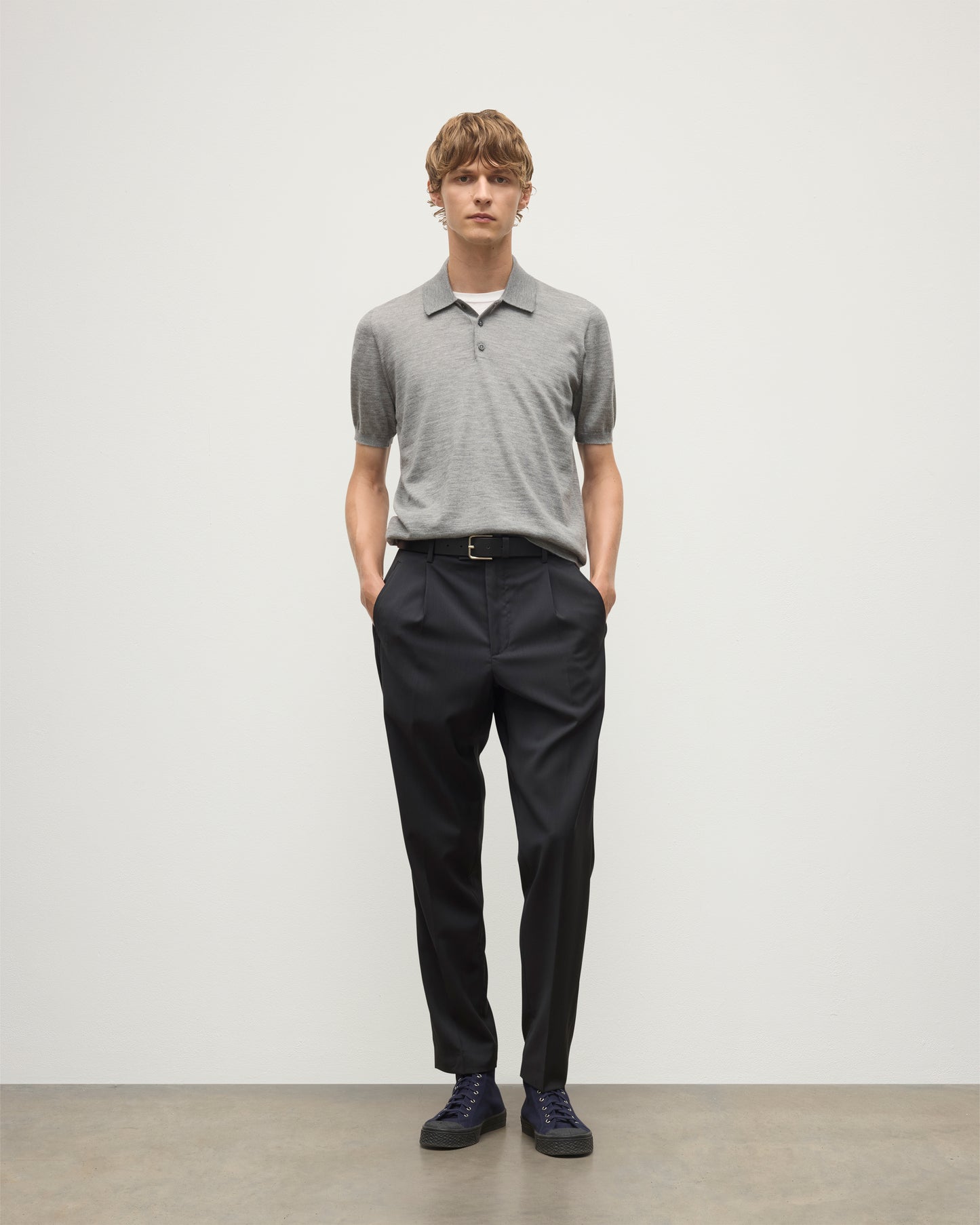 MODEL WEARS JOHNSTONS OF ELGIN MENS FIN SHORT SLEEVE SUPERFINE POLOSHIRT GREY OVER A WHITE T-SHIRT WITH NAVY TROUSERS KAI05741HA4253