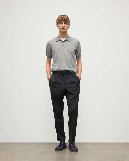 MODEL WEARS JOHNSTONS OF ELGIN MENS FIN SHORT SLEEVE SUPERFINE POLOSHIRT GREY OVER A WHITE T-SHIRT WITH NAVY TROUSERS KAI05741HA4253