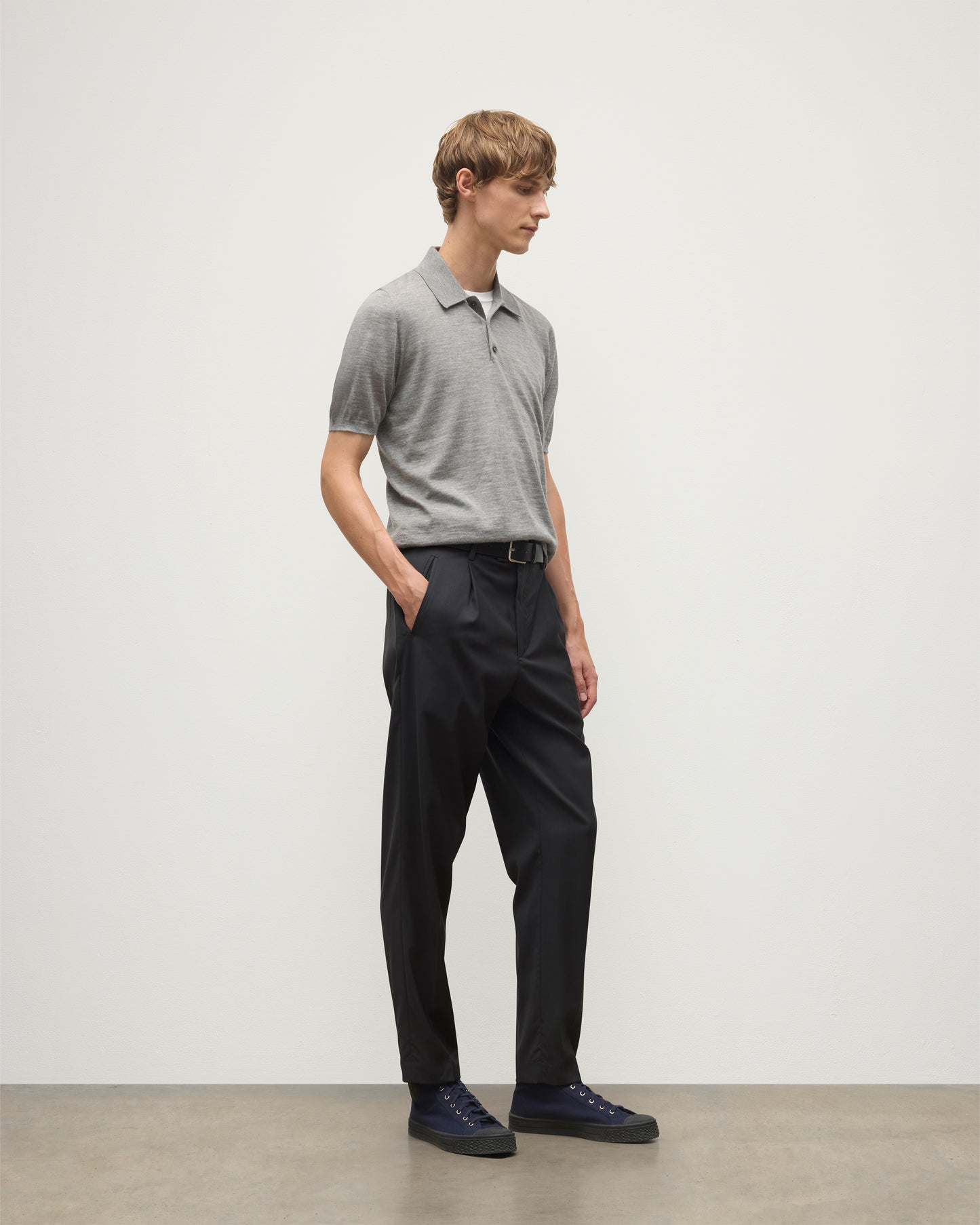 MODEL WEARS JOHNSTONS OF ELGIN MENS FIN SHORT SLEEVE SUPERFINE POLOSHIRT GREY OVER A WHITE T-SHIRT WITH NAVY TROUSERS KAI05741HA4253