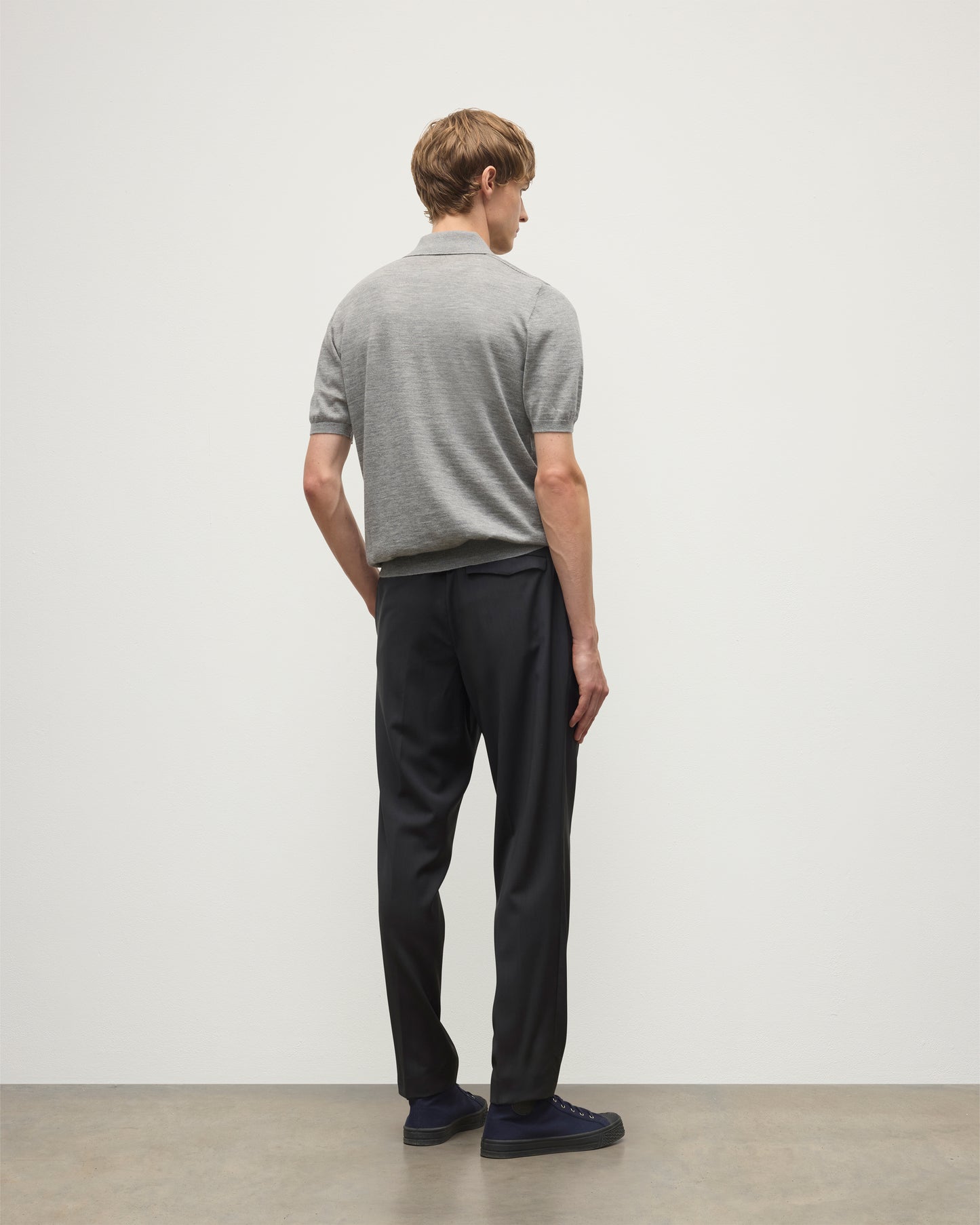 MODEL WEARS JOHNSTONS OF ELGIN MENS FIN SHORT SLEEVE SUPERFINE POLOSHIRT GREY OVER A WHITE T-SHIRT WITH NAVY TROUSERS KAI05741HA4253