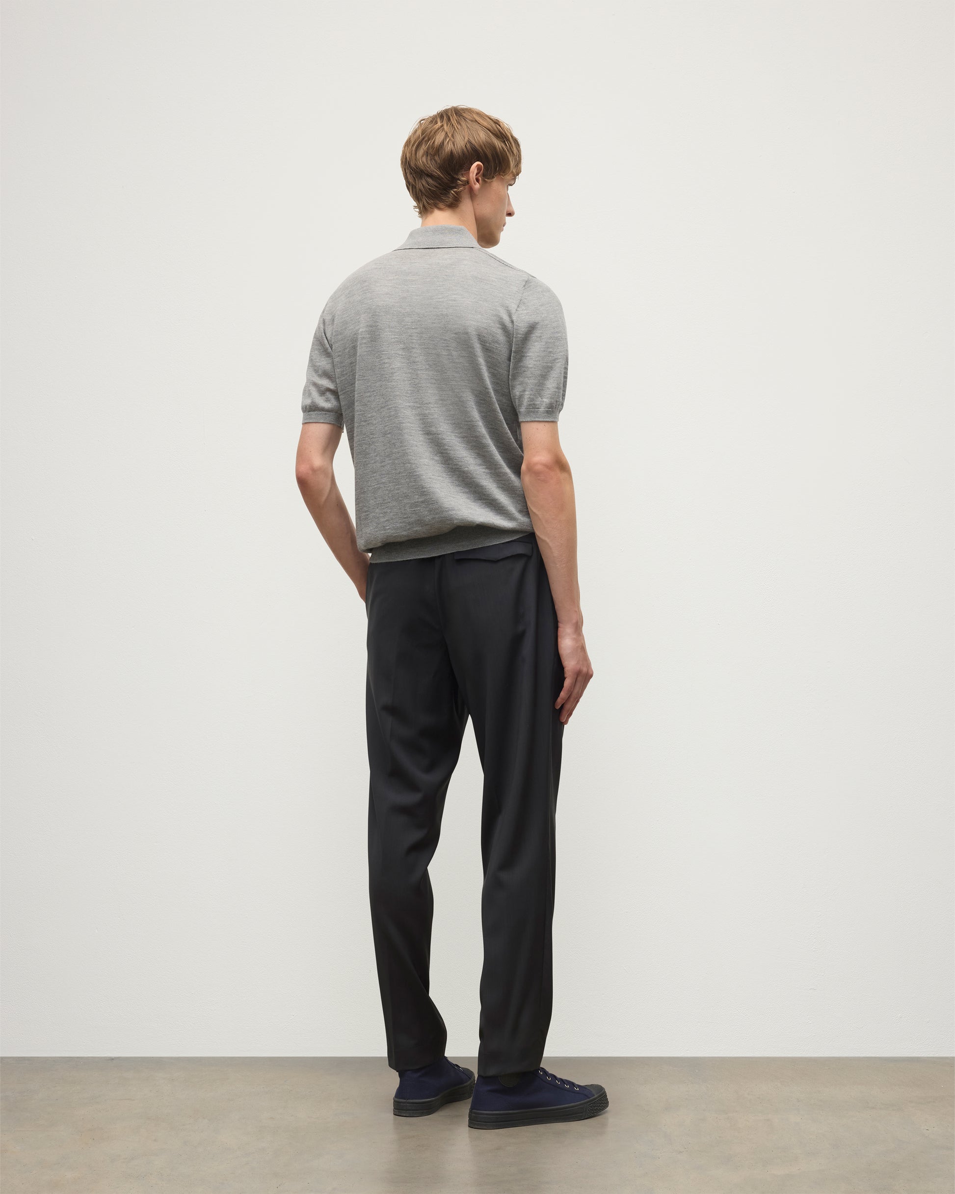 MODEL WEARS JOHNSTONS OF ELGIN MENS FIN SHORT SLEEVE SUPERFINE POLOSHIRT GREY OVER A WHITE T-SHIRT WITH NAVY TROUSERS KAI05741HA4253