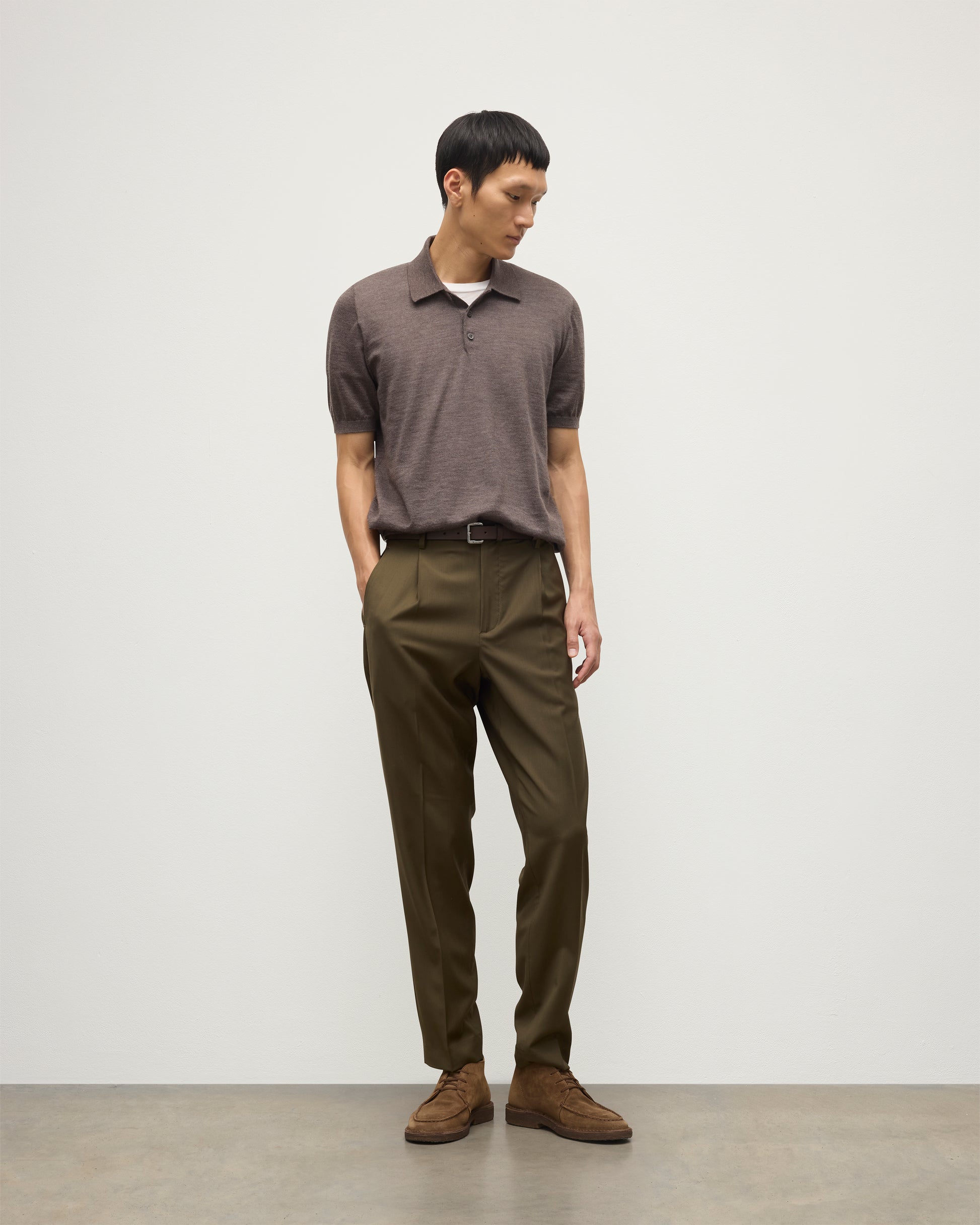 MODEL WEARS JOHNSTONS OF ELGIN MENS FIN SHORT SLEEVE SUPERFINE POLOSHIRT LIGHT BROWN OVER A WHITE T-SHIRT WITH OLIVE GREEN TROUSERS KAI05741HB7092