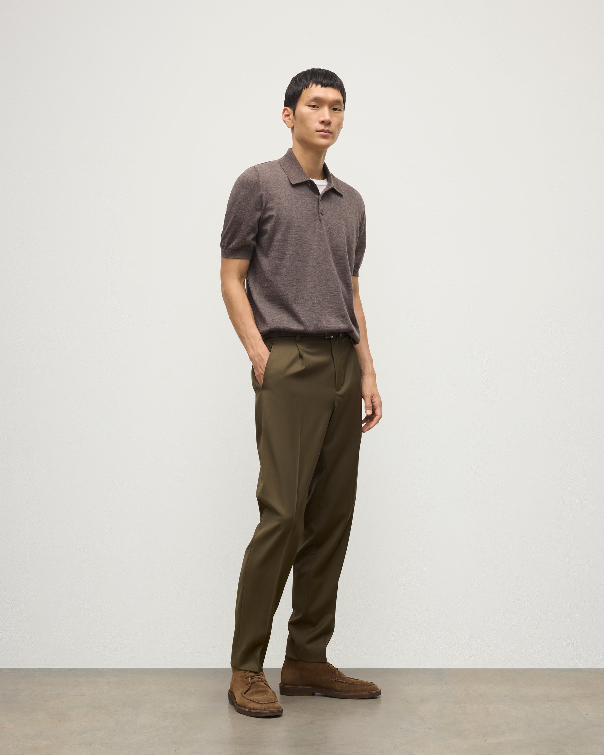 MODEL WEARS JOHNSTONS OF ELGIN MENS FIN SHORT SLEEVE SUPERFINE POLOSHIRT LIGHT BROWN OVER A WHITE T-SHIRT WITH OLIVE GREEN TROUSERS KAI05741HB7092