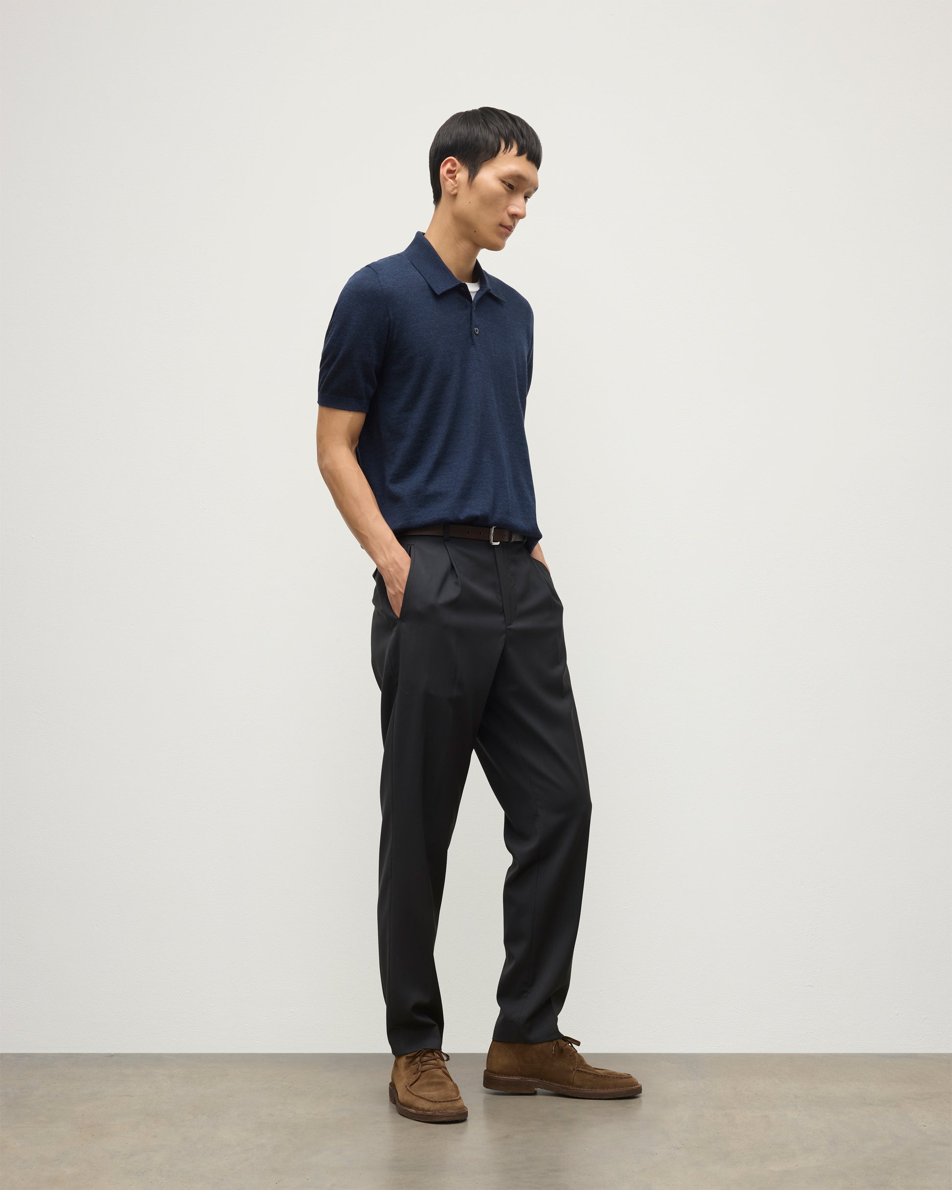 MODEL WEARS JOHNSTONS OF ELGIN MENS FIN SHORT SLEEVE SUPERFINE POLOSHIRT NAVY OVER A WHITE T-SHIRT WITH NAVY TROUSERS KAI05741HD7350