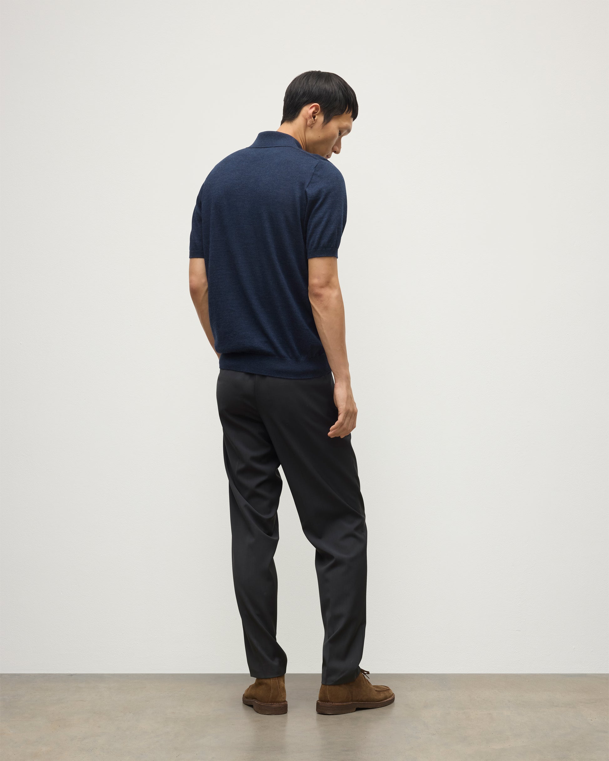 MODEL WEARS JOHNSTONS OF ELGIN MENS FIN SHORT SLEEVE SUPERFINE POLOSHIRT NAVY OVER A WHITE T-SHIRT WITH NAVY TROUSERS KAI05741HD7350