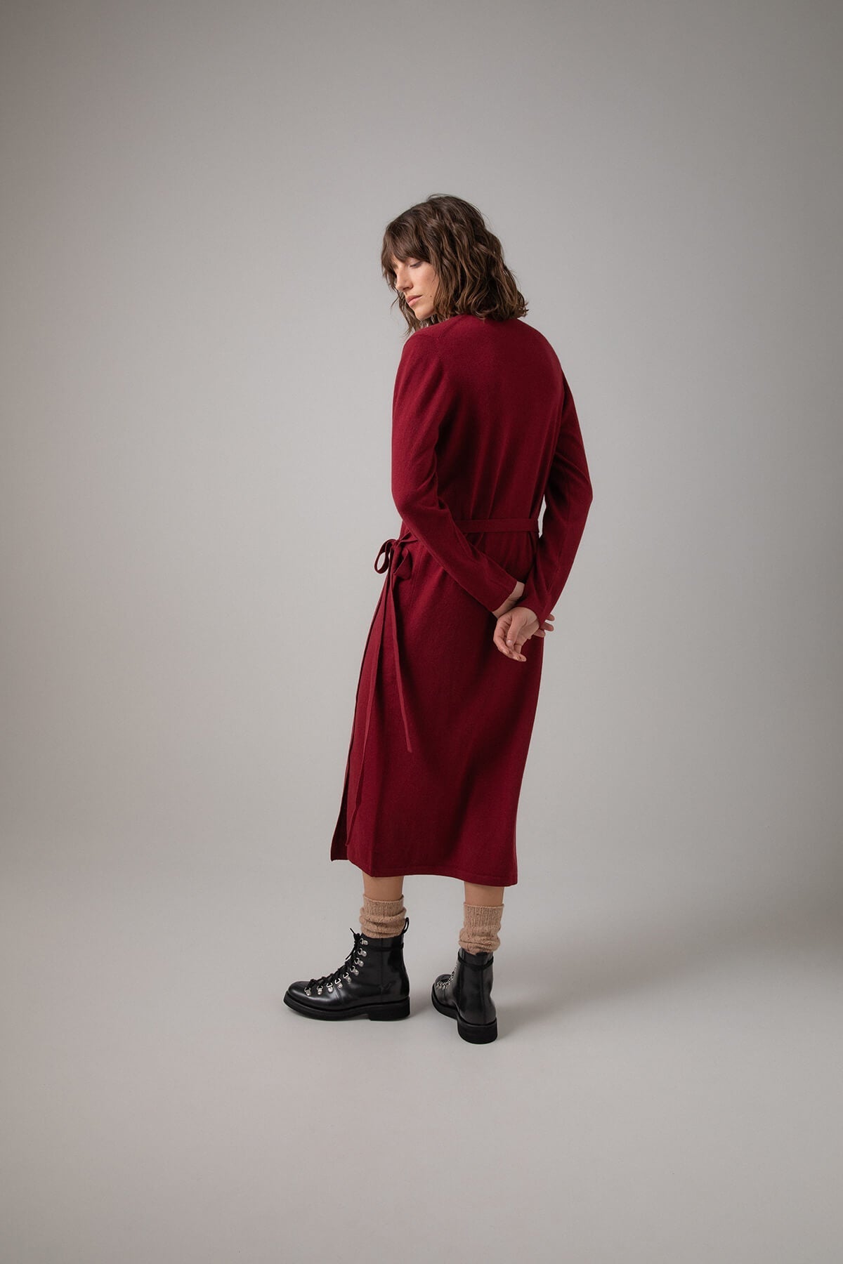 Back of Johnstons of Elgin Ballet Wrap Cashmere Dress in Wine worn with Cashmere Socks & Shoes on a grey background KAP05047SE6162