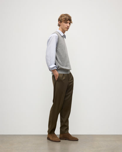 MODEL WEARS JOHNSTONS OF ELGIN MENS LENNOX SLEEVELESS CREW GREY 100% CASHMERE OVER A LIGHT BLUE SHIRT WITH OLIVE GREEN TROUSERS KAP05243HA0400