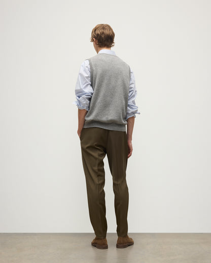 MODEL WEARS JOHNSTONS OF ELGIN MENS LENNOX SLEEVELESS CREW GREY 100% CASHMERE OVER A LIGHT BLUE SHIRT WITH OLIVE GREEN TROUSERS KAP05243HA0400