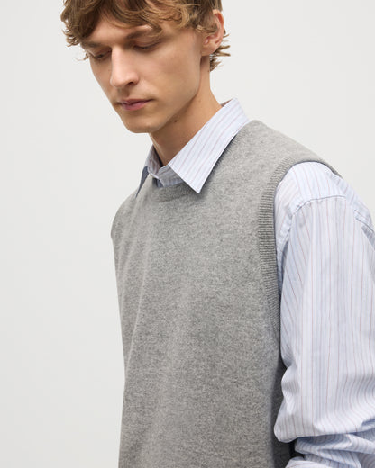 MODEL WEARS JOHNSTONS OF ELGIN MENS LENNOX SLEEVELESS CREW GREY 100% CASHMERE OVER A LIGHT BLUE SHIRT KAP05243HA0400