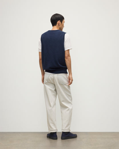 MODEL WEARS JOHNSTONS OF ELGIN MENS LENNOX SLEEVELESS CREW NAVY 100% CASHMERE, OVER A WHITE SHORT SLEEVE T-SHIRT WITH WHITE JEANS KAP05243HD7350