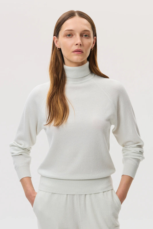 Model wears Johnstons of Elgin SS25 Women's Knitwear White Classic Cashmere Roll Neck Sweater with 
 matching cashmere culottes KAP05275HA0346