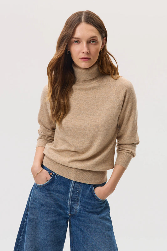 Model wears Johnstons of Elgin SS25 Women's Knitwear Oatmeal Classic Cashmere Roll Neck Jumper with blue jeans KAP05275HB0210