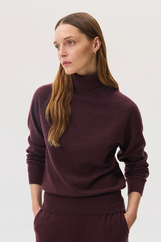 Model wears Johnstons of Elgin SS25 Women's Knitwear Rosewood Classic Cashmere Roll Neck Sweater with matching cashmere culottes KAP05275SB7089