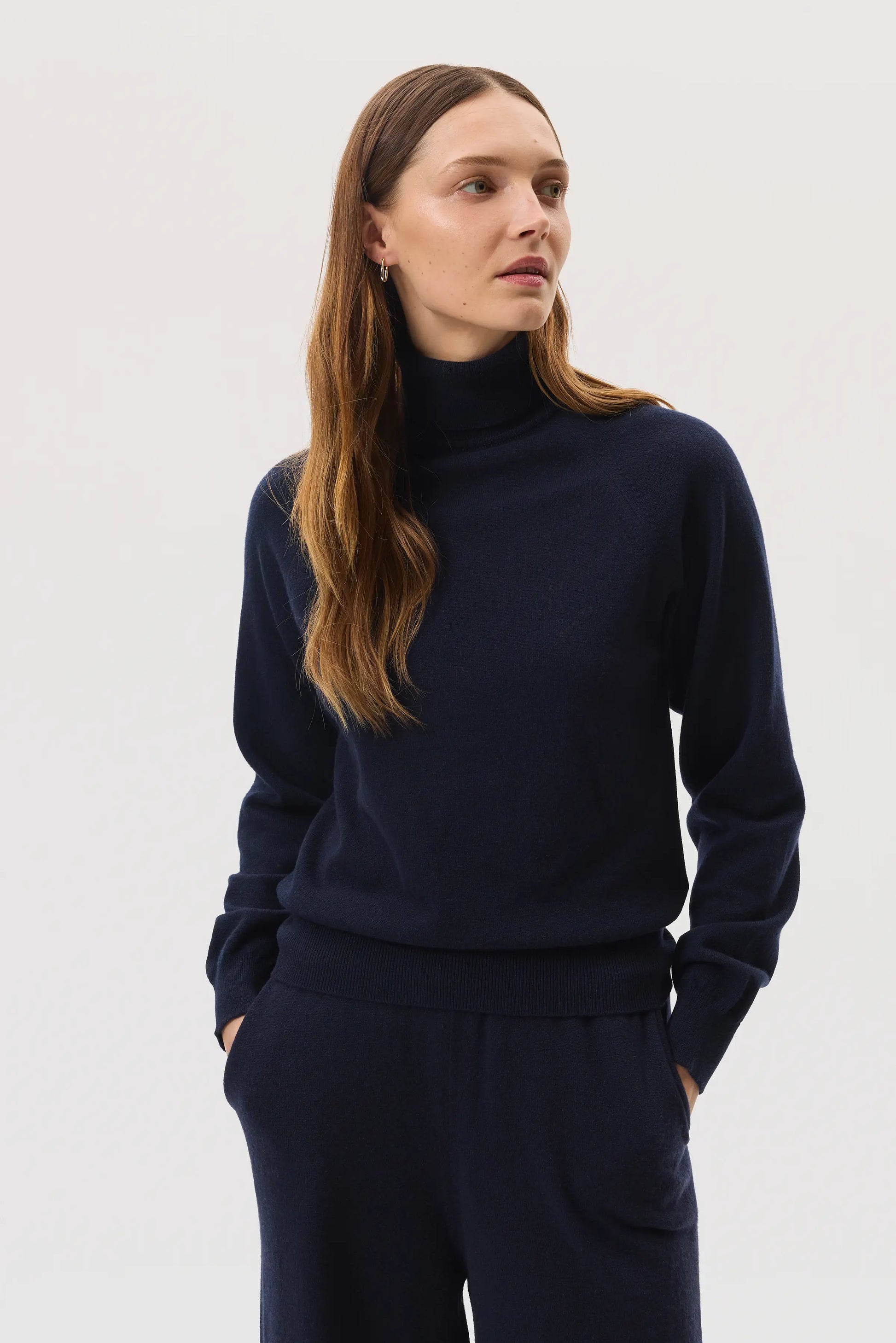 Model wears Johnstons of Elgin SS25 Women's Knitwear Navy Classic Cashmere Roll Neck Sweater with matching cashmere culottes KAP05275SD7286