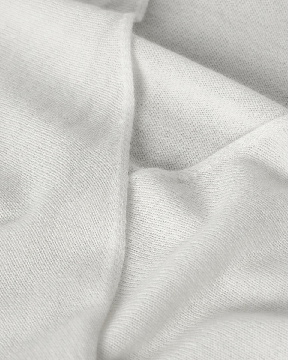 Johnstons of Elgin AW25 Women's Knitwear White Featherlight Cashmere Ballet Wrap with white trousers on a light background KAP05408HA0346