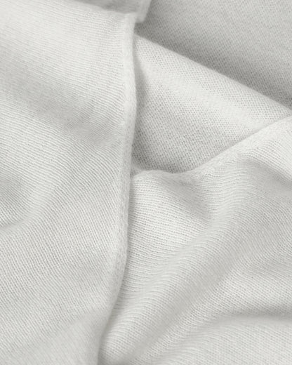 Johnstons of Elgin AW25 Women's Knitwear White Featherlight Cashmere Ballet Wrap with white trousers on a light background KAP05408HA0346