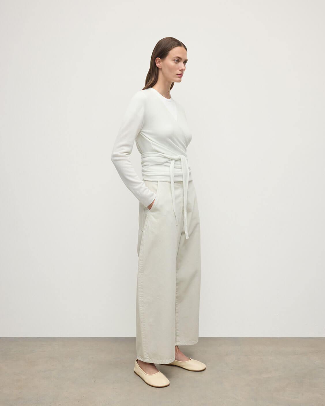 Model wearing Johnstons of Elgin AW25 Women's Knitwear White Featherlight Cashmere Ballet Wrap with white trousers on a light background KAP05408HA0346