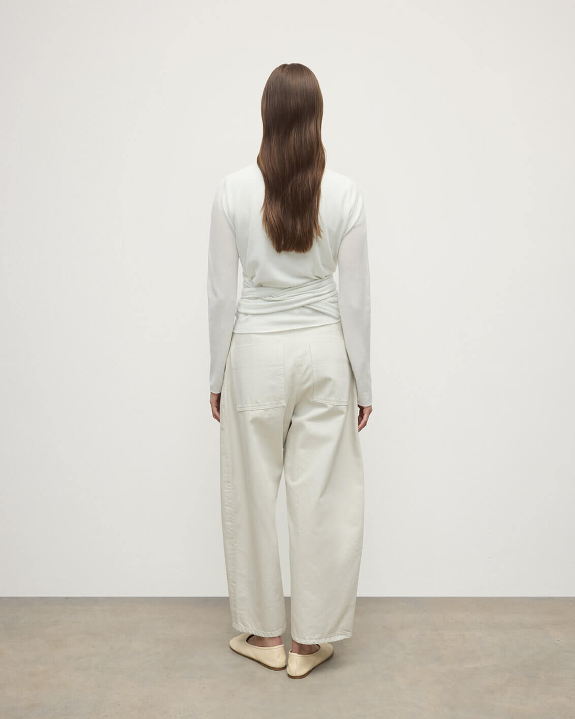 Model wearing Johnstons of Elgin AW25 Women's Knitwear White Featherlight Cashmere Ballet Wrap with white trousers on a light background KAP05408HA0346