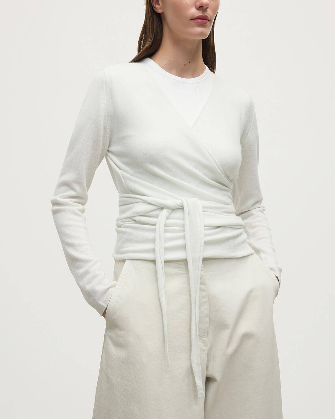 Model wearing Johnstons of Elgin AW25 Women's Knitwear White Featherlight Cashmere Ballet Wrap with white trousers on a light background KAP05408HA0346