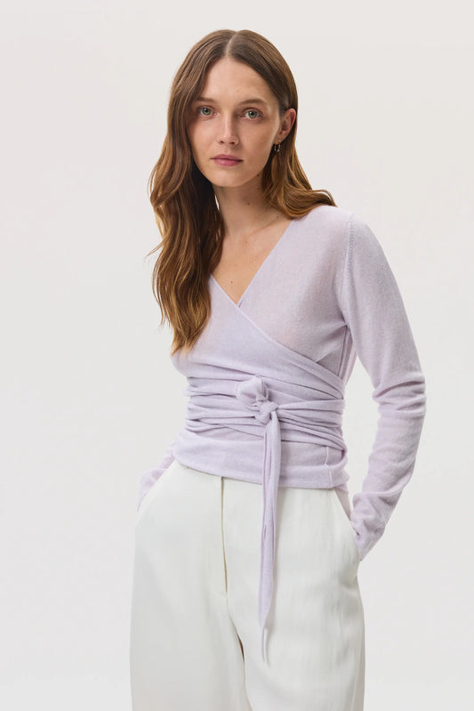 Model wears Johnstons of Elgin SS25 Women's Knitwear Lavender Featherlight Cashmere Ballet Wrap with white wide leg trousers KAP05408HD0086