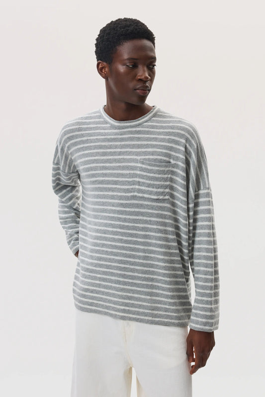 Model wears Johnstons of Elgin SS25 Men's Knitwear Light Grey & White Cashmere Jersey Stripe Oversized T-Shirt with white trousers  KAP05442Q25132