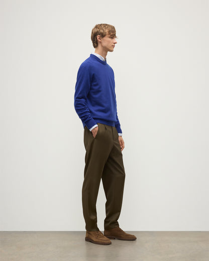MODEL WEARS JOHNSTONS OF ELGIN MENS RORY CREW CLASSIC JUMPER BLUE 100% CASHMERE OVER A LIGHT BLUE SHIRT WITH OLIVE GREEN TROUSERS KAP05471SD5326