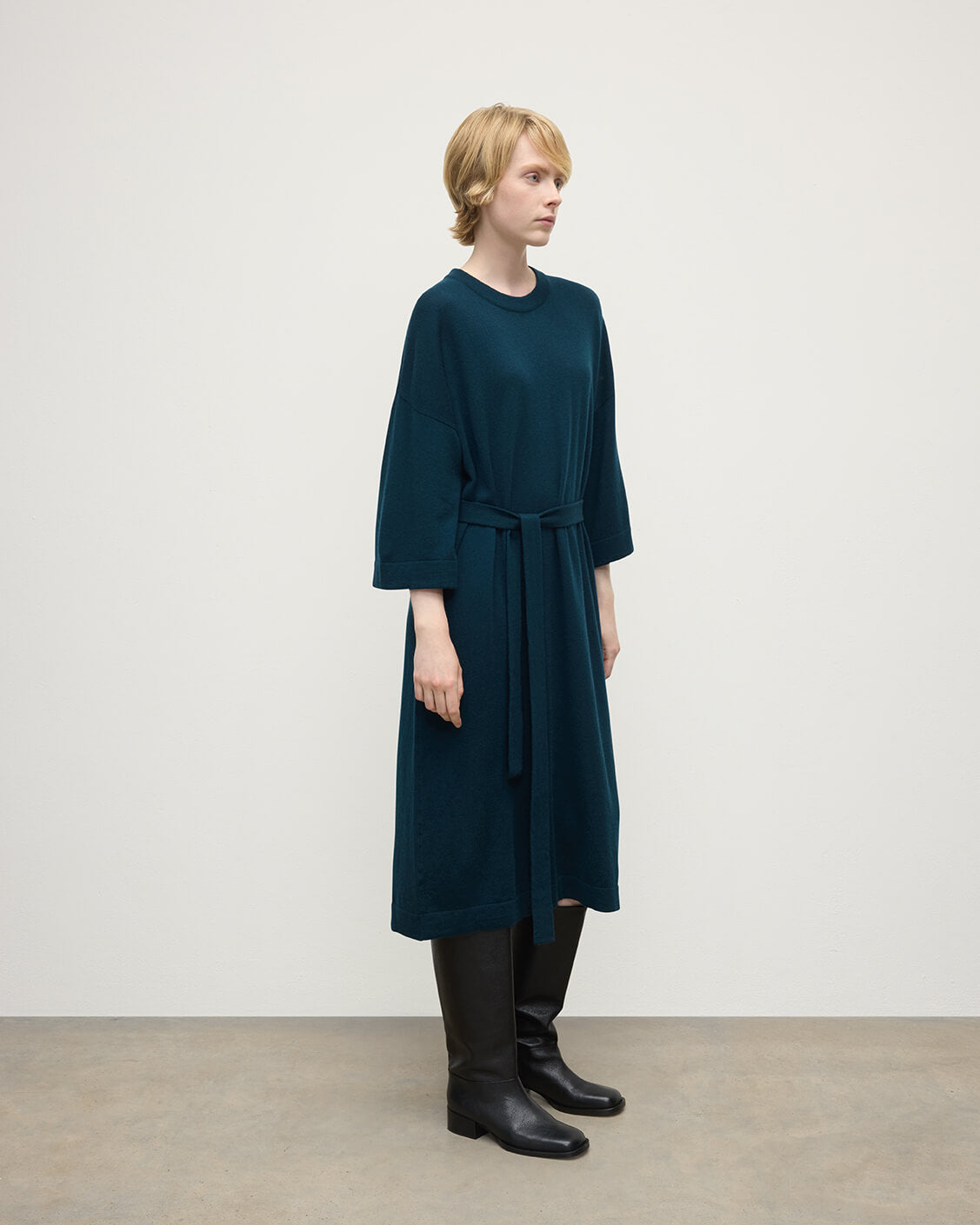 Model wears Johnstons of Elgin AW25 Women's Knitwear Bottle Green Tie-Waist Cashmere Green Jumper Dress Side View  KAP05490SC7341