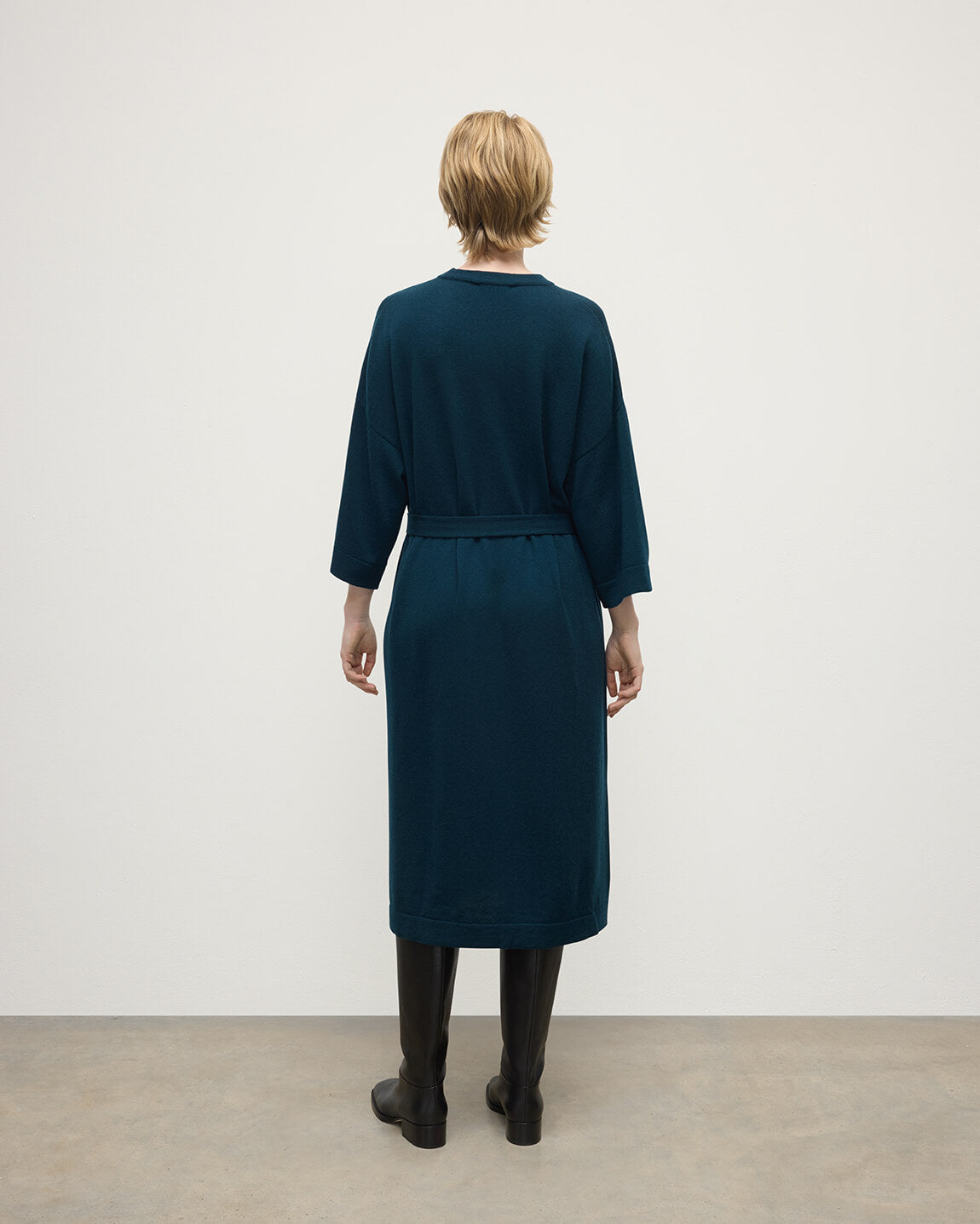 Model wears Johnstons of Elgin AW25 Women's Knitwear Bottle Green Tie-Waist Cashmere Green Jumper Dress Back View  KAP05490SC7341