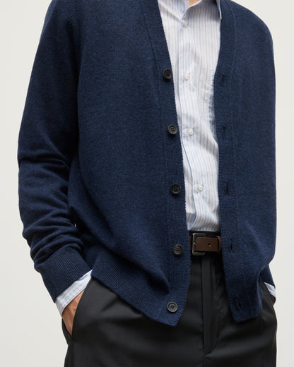 MODEL WEARS JOHNSTONS OF ELGIN MENS RORY VEE NECK CLASSIC CARDIGAN NAVY 100% CASHMERE OVER A LIGHT BLUE SHIRT KAP05576HD7350