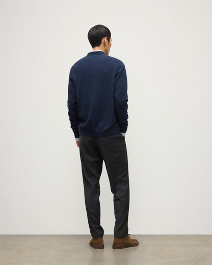 MODEL WEARS JOHNSTONS OF ELGIN MENS RORY VEE NECK CLASSIC CARDIGAN NAVY 100% CASHMERE OVER A LIGHT BLUE SHIRT WITH NAVY TROUSERS KAP05576HD7350