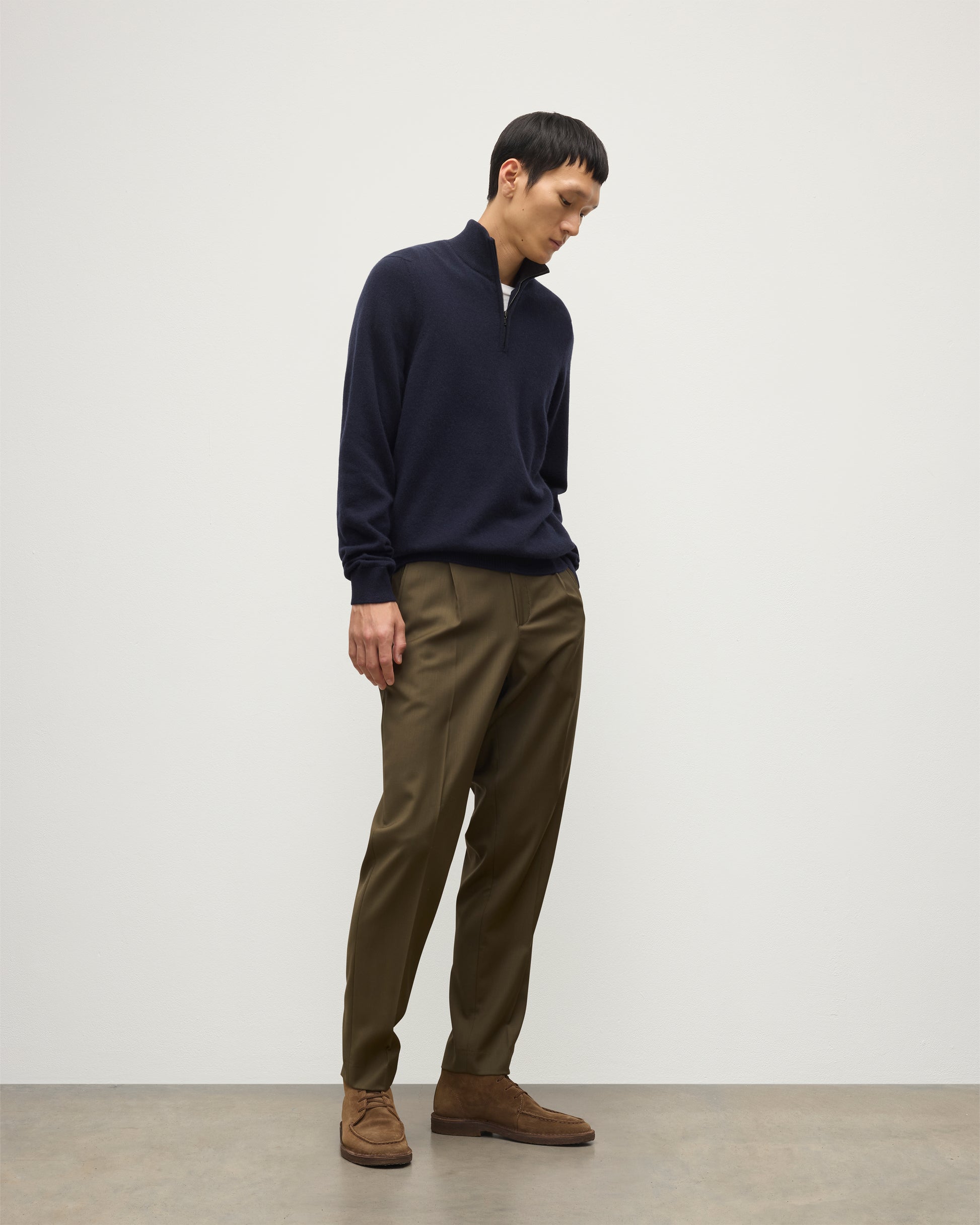 MODEL WEARS JOHNSTONS OF ELGIN MENS RORY CLASSIC HALF ZIP SWEATER CONTRAST TRIM NAVY & CHARCOAL 100% CASHMERE, OVER A WHITE T-SHIRT WITH OLIVE GREEN TROUSERS KAP05577Q26187