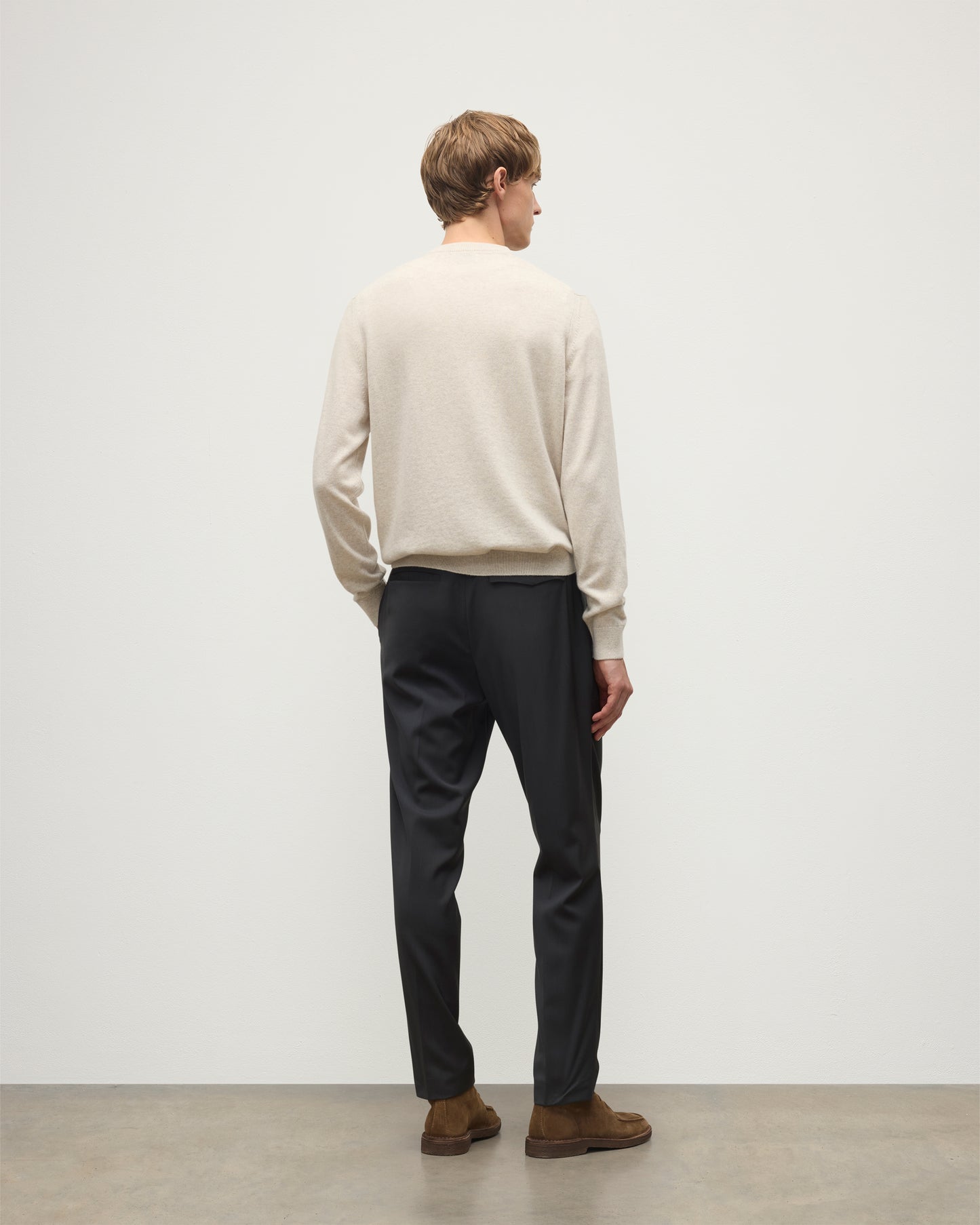 MODEL WEARS JOHNSTONS OF ELGIN MENS RORY VEE NECK CLASSIC JUMPER NATURAL 100% CASHMERE, OVER A WHITE T-SHIRT WITH NAVY TROUSERS  KAP05594HA0402