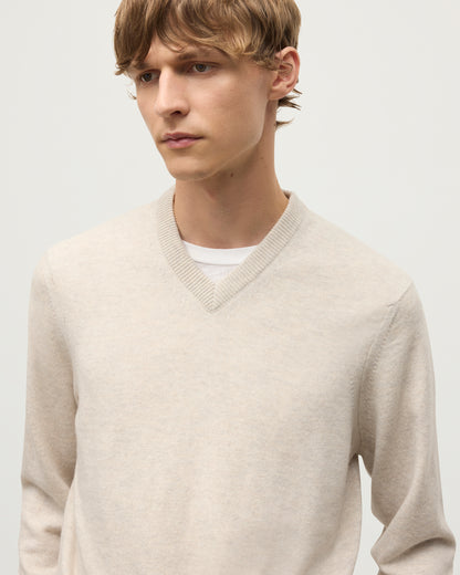 MODEL WEARS JOHNSTONS OF ELGIN MENS RORY VEE NECK CLASSIC JUMPER NATURAL 100% CASHMERE, OVER A WHITE T-SHIRT WITH NAVY TROUSERS  KAP05594HA0402