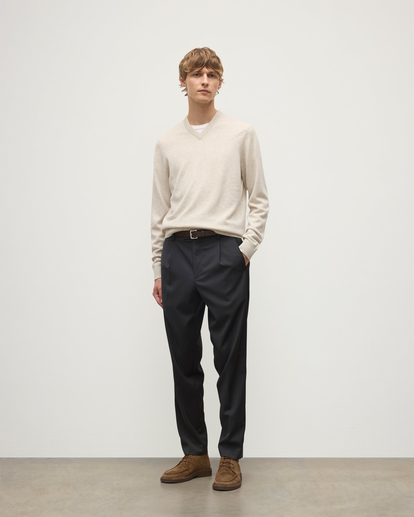 MODEL WEARS JOHNSTONS OF ELGIN MENS RORY VEE NECK CLASSIC JUMPER NATURAL 100% CASHMERE, OVER A WHITE T-SHIRT WITH NAVY TROUSERS  KAP05594HA0402